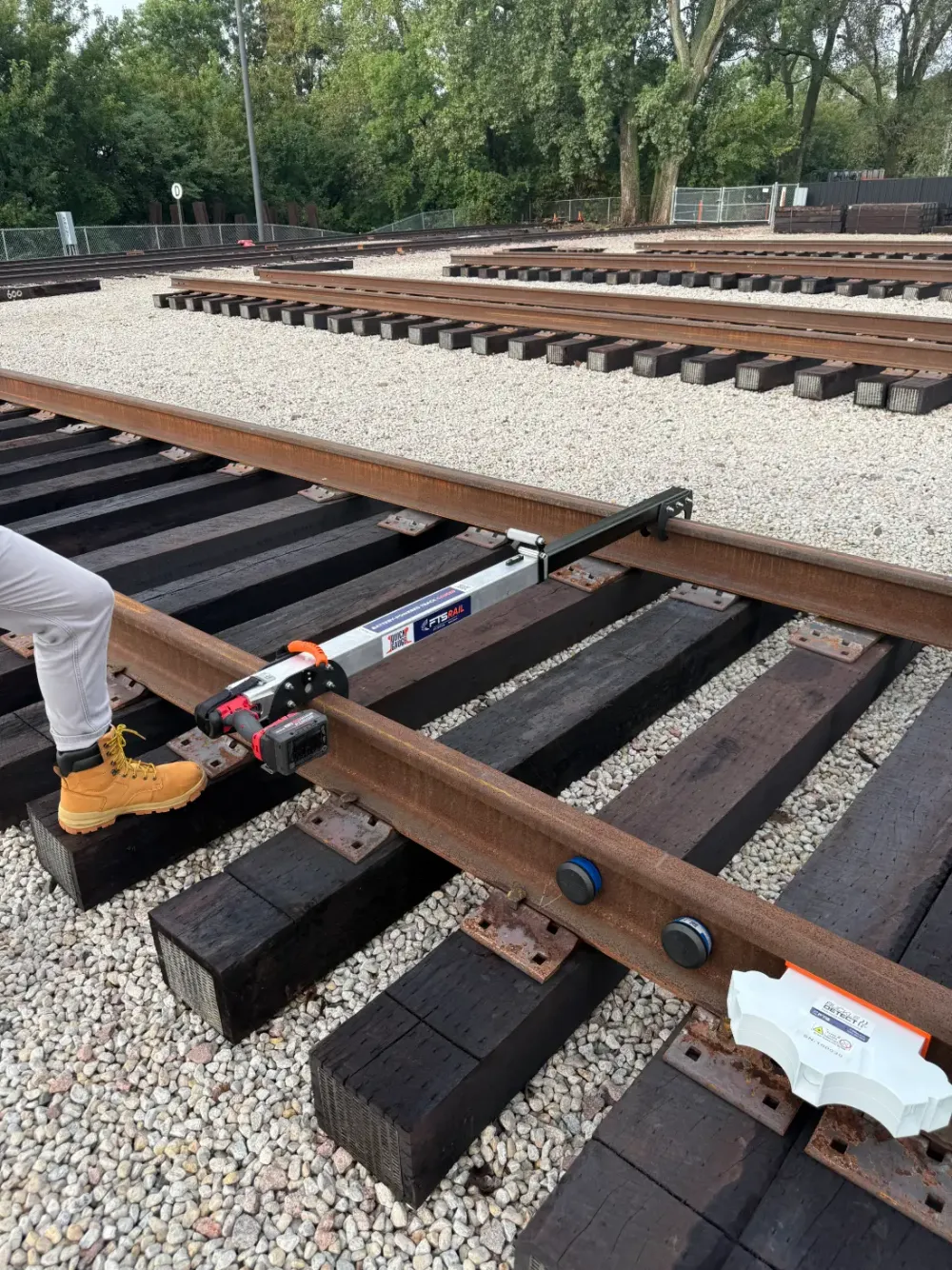 Close-up of the FTS Rail Quick Gauge hooked between railroad rails