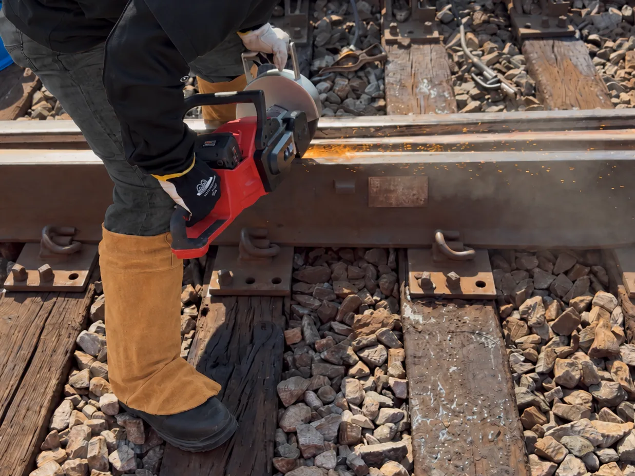 Railroad worker using the battery-powered Frog Grinder on track