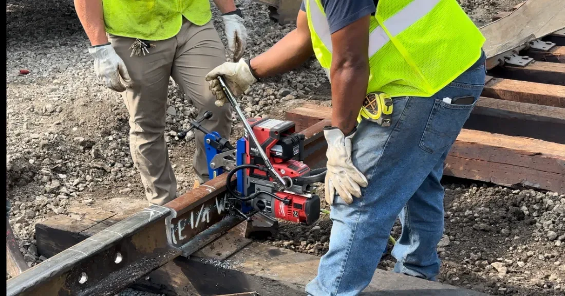 RailEase rail drill clamped to rail in a yard